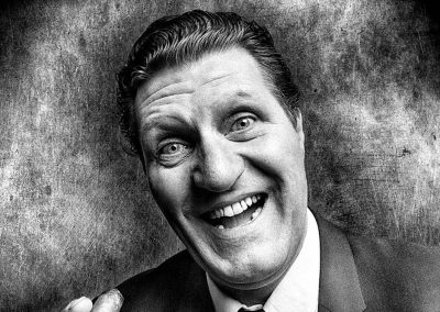 Image shows a black and white image of Tommy Cooper