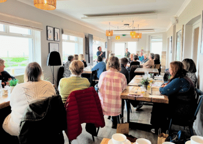 People sat in a room listening to a woman with a microphone