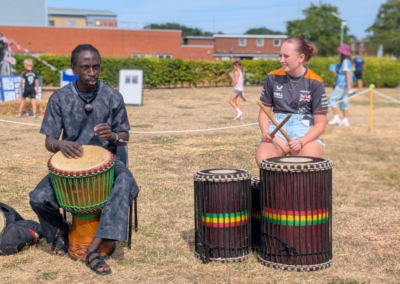 Image of a man and teenager playing drums in a field