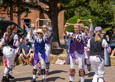 Group of people in purple and white outfits dancing with hands raised above their heads
