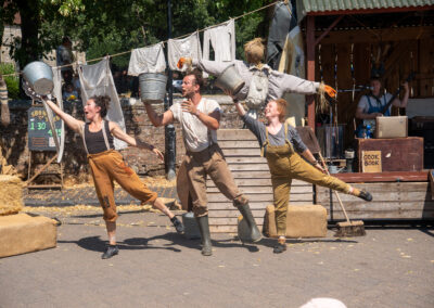 3 Farm Yard Circus Performers on their tip toes with their arms outreached